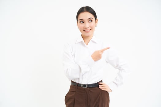 Business. Corporate asian woman points finger right, shows advertisement, banner promo, stands over white background photo