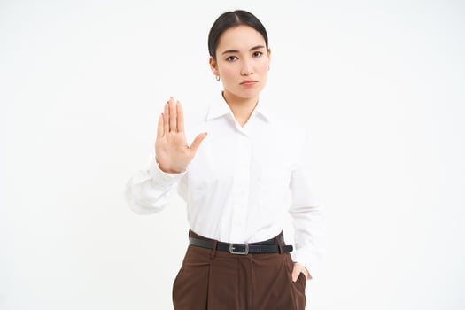 Stop. Strict and serious lady boss, asian woman shows extended hand, rejection, prohibit gesture, white background photo
