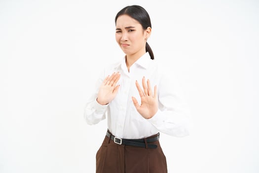Stop, stay back. Young asian woman rejects smth, pulls away, holds hands extended to refuse, disapprove something, white background photo