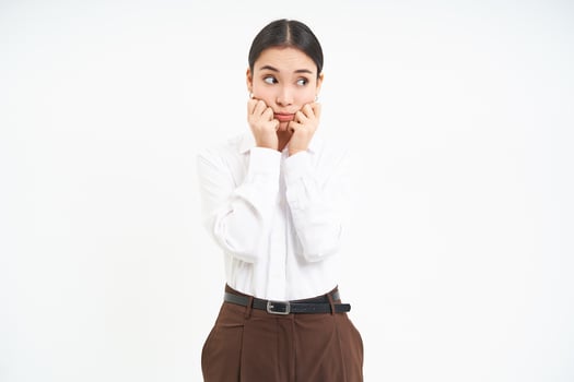 Worried young asian corporate woman, office lady looks anxous and unsure aside, white background photo