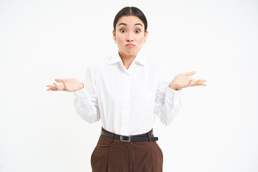 Clueless asian corporate woman, shrugs shoulders with puzzled face expression, stands confused, white background photo