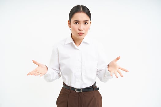 Image of confused asian saleswoman, spreads hands sideways with clueless face expression, shrugs shoulders, white background photo