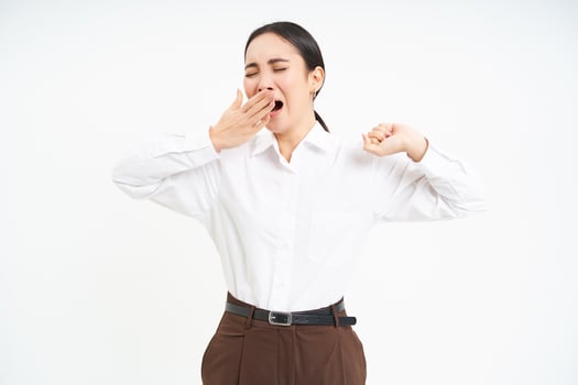 Tired asian corporate woman, yawns and stretches her back from fatigue after work, isolated on white background photo