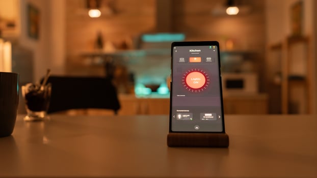 Controlling light bulb temperature and intensity with smartphone application. Phone with touching screen late at night with technology to change lights in home. photo