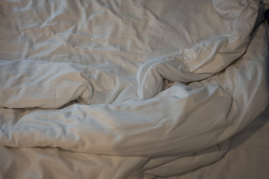 Unmade white bedding sheets and pillow, Messy bed after night sleep concept. photo