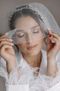 Morning of bride before the wedding. Beautiful young woman with long veil in a white robe. Natural beauty and professional make-up.Girl in white lace boudoir dress. photo