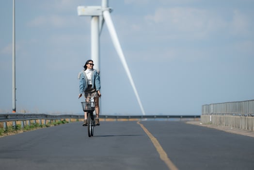 Young woman riding a bike on a road in a windmill. photo