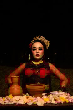 Close up shot of an Asian girl in red clothes sitting on her knees in front of a flower offering photo