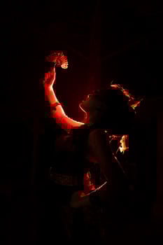 silhouette of a female dancer holding jewelry in the middle of the stillness of the night with red light photo