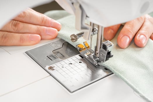 Female hands stitching white fabric on modern sewing machine at workplace in atelier photo