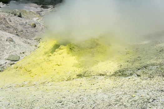 smoking solfatara among sulfur deposits on the slope of the volcano photo