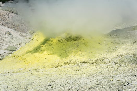 yellow cone of crystallized sulfur around a smoking solfatara on the slope of a volcano photo