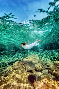 Woman swimming near rock photo