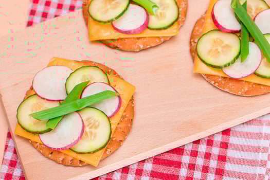 Light Breakfast. Quick and Healthy Sandwich. Fresh Cucumber and Radish with Green Onions and Cheese on Crispy Cracker on Wooden Cutting Board photo