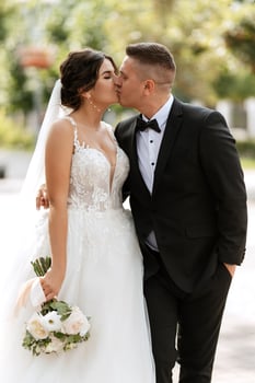 the groom in a brown suit and the bride in a white dress photo
