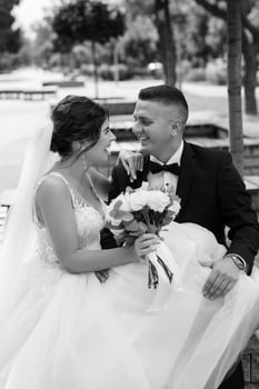 the groom in a brown suit and the bride in a white dress photo