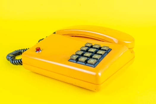 yellow plastic vintage telephone with red button on a yellow background photo