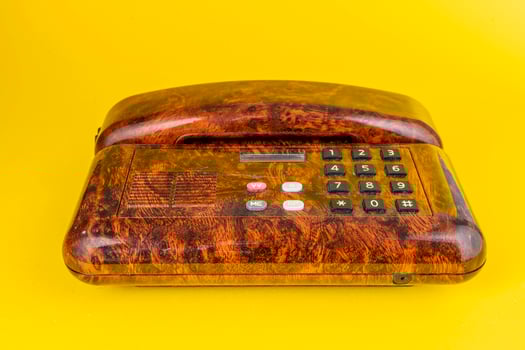 vintage telephone in imitation briar wood over a yellow background photo