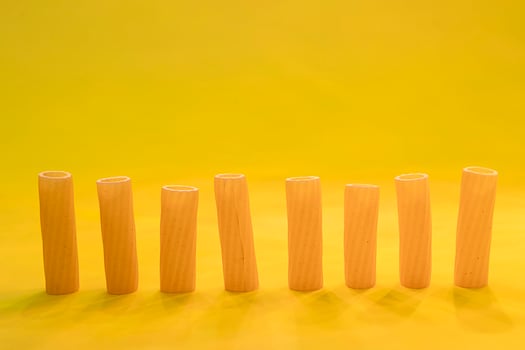 small group of fresh macaroni rigati lined up on yellow background photo