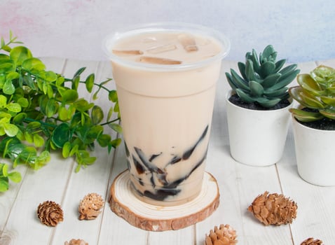 frozen milk with grass jelly served om disposable glass isolated on wooden board top view of hong kong drink photo