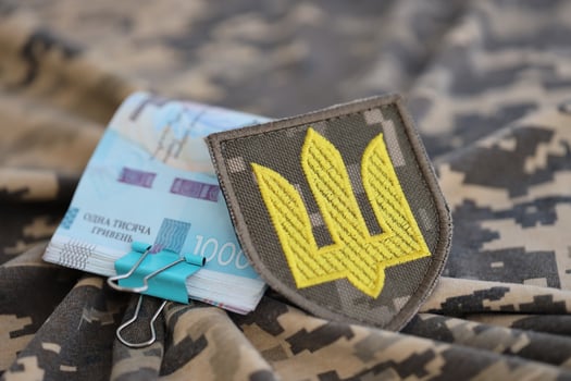 Ukrainian army symbol and bunch of hryvnia bills on military uniform. Payments to soldiers of the Ukrainian army, salaries to the military photo