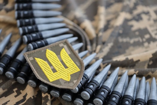 Ukrainian army symbol on machine gun belt lies on ukrainian pixeled military camouflage photo