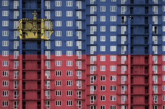 Liechtenstein flag depicted in paint colors on multi-storey residental building under construction. Textured banner on brick wall background photo