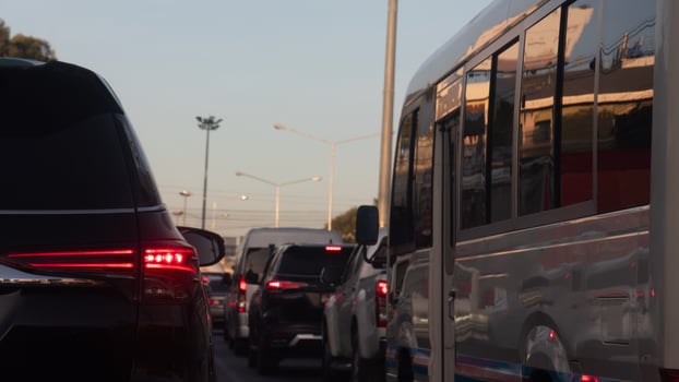 Rear side of black car with turn on brake light on the road. Traffic jam with many cars connected in a long queue. Environment of city in the morning. photo