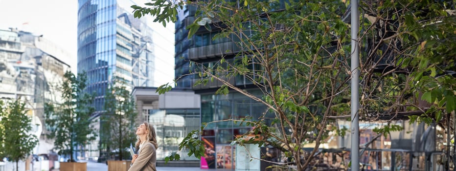 Vertical shot of corporate woman in beige suit standing outside on street, drinks morning coffee takeaway before work photo