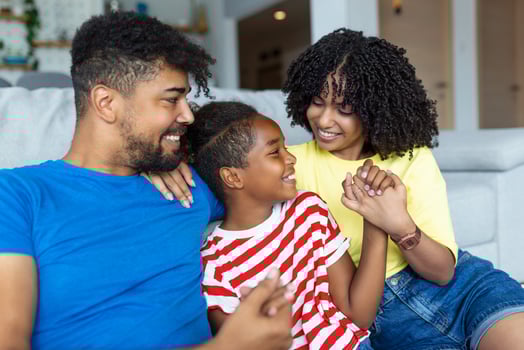 Loving diverse parents spend time with little adorable daughter have fun together at modern home smiling laughing, close up. Happy multi-ethnic family concept photo