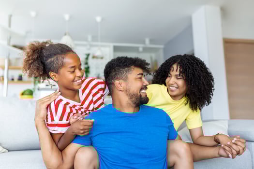 Portrait attractive multi-ethnic wife husband and kid indoors. Close up married couple with little pretty daughter sitting together smiling looking at camera. Concept friendly wellbeing happy family photo