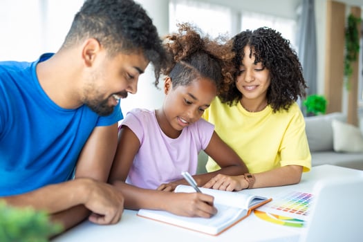 A mixed race husband and wife doing homework with their daughter while social distancing and isolating at home during the Covid-19 pandemic. photo