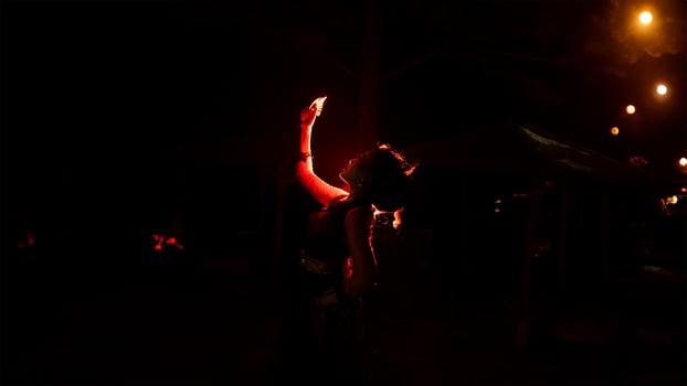 the silhouette of a woman looking at her jewelry with a face full of sadness and the fire burning around her photo