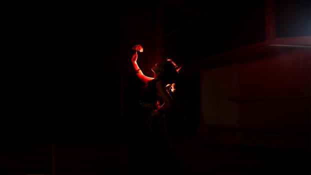 the silhouette of a female dancer holding jewelry that looks like a reflection reflecting in the dim light photo