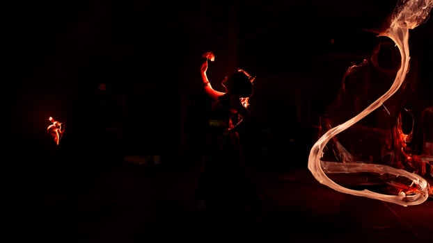 the silhouette of a female dancer holding jewelry shines brightly around the flames and looks bold in the dark photo