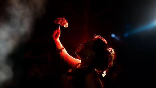 the silhouette of a female dancer holding jewelry shines brightly around the flames and looks bold in the dark photo