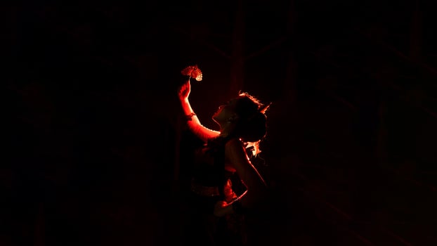 the silhouette of a female dancer holding jewelry that looks like a reflection reflecting in the dim light photo