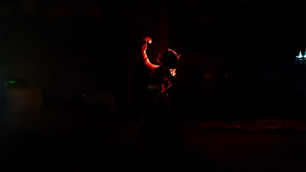 the silhouette of a female dancer holding jewelry that looks like a reflection reflecting in the dim light photo