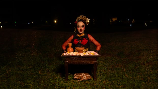a female dancer looks focused on her ritual with a peaceful facial expression in front of offerings that look fresh and lively photo