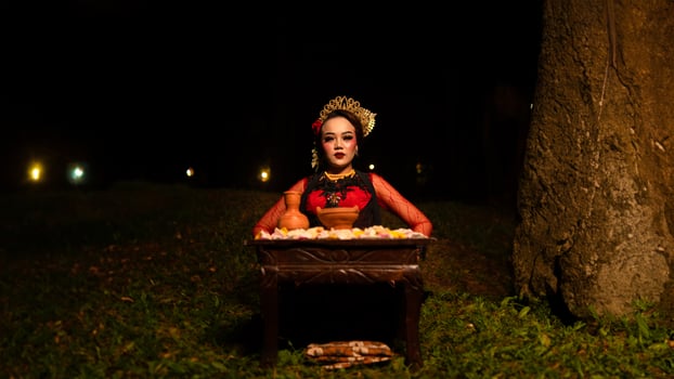 a female dancer looks focused on her ritual with a peaceful facial expression in front of offerings that look fresh and lively photo