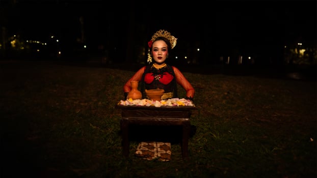 a female dancer who looks beautiful in a red costume performs a ritual that radiates an aura of beauty and purity photo