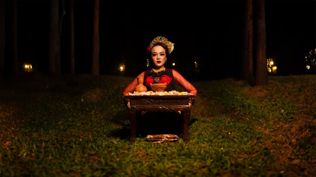 a female dancer looks focused on her ritual with a peaceful facial expression in front of offerings that look fresh and lively photo
