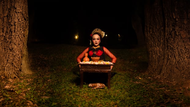 a female dancer looks focused on her ritual with a peaceful facial expression in front of offerings that look fresh and lively photo