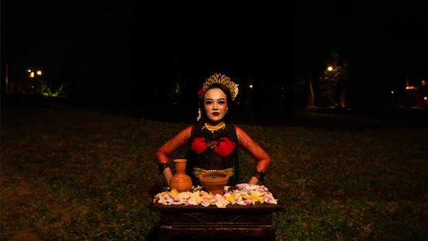 a female dancer performs a ritual that creates a magical and mystical atmosphere in front of flower offerings photo