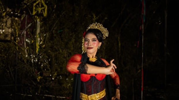 a Balinese dancer wearing gold jewelry and dancing with confidence on the stage photo