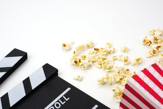 Clapperboard or movie slate black color with popcorn on white background. Cinema industry, video production and film concept. photo