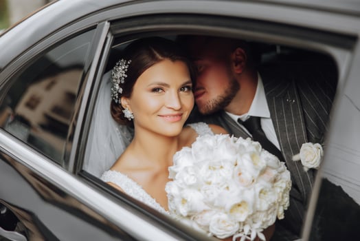 A modern bride and groom in a lace dress in a car window. Beautiful and smiling newlyweds. Happy holiday. photo