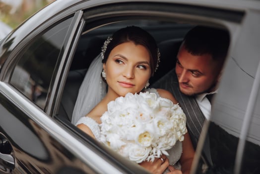 A modern bride and groom in a lace dress in a car window. Beautiful and smiling newlyweds. Happy holiday. photo