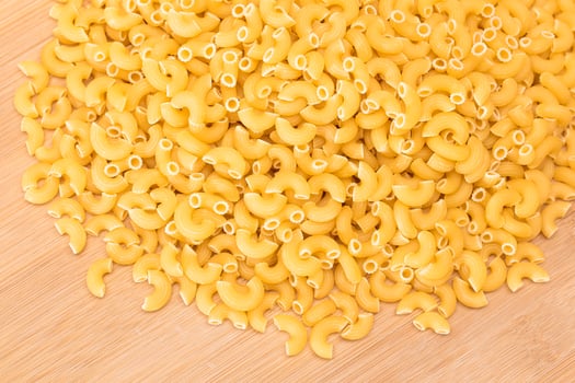 A Heap of Uncooked Chifferi Rigati Pasta on Wooden Kitchen Board. Fat and Unhealthy Food. Classic Dry Macaroni. Italian Culture and Cuisine. Raw Pasta photo