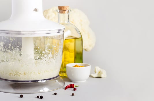 Blender bowl with freshly prepared cauliflower rice, selective focus photo